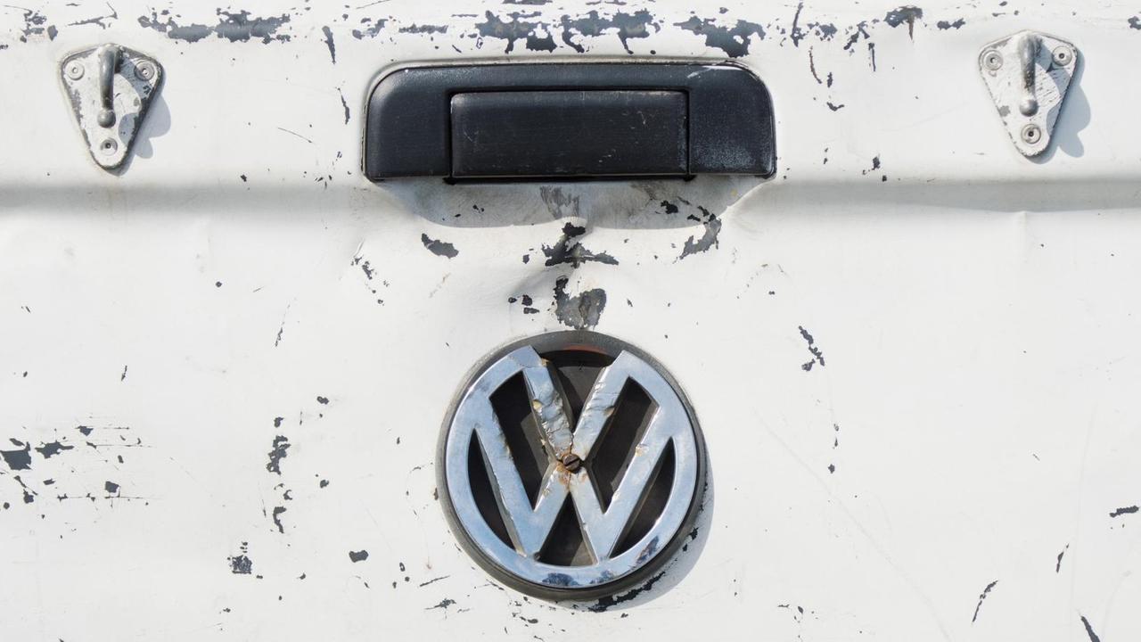 Ein beschädigtes VW Logo hängt am zerkratzten Kofferraum eines Volkswagen in Wolfsburg.