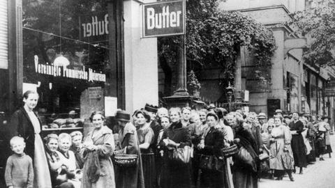 Schwarzweiß Fotografie mit einer Schlange von Menschen vor einem Lebensmittelladen im 1. Weltkrieg.
