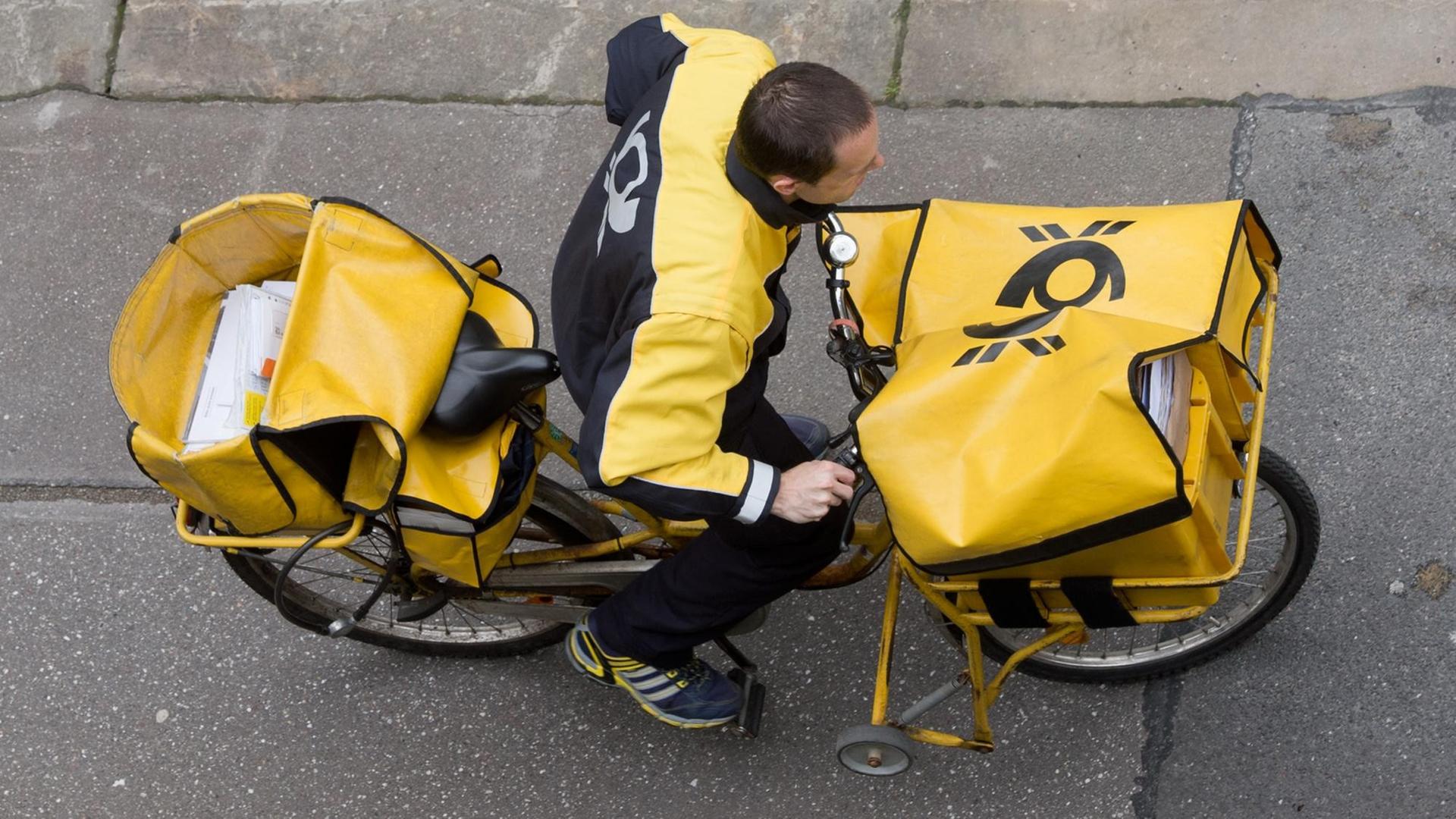 Ein Briefträger der Deutschen Post sitzt auf seinem Fahrrad und verteilt Briefe.