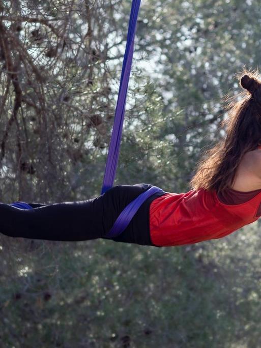 Eine junge Frau trainiert am Aerial Silk Tuch in der Natur. (Symbolfoto)