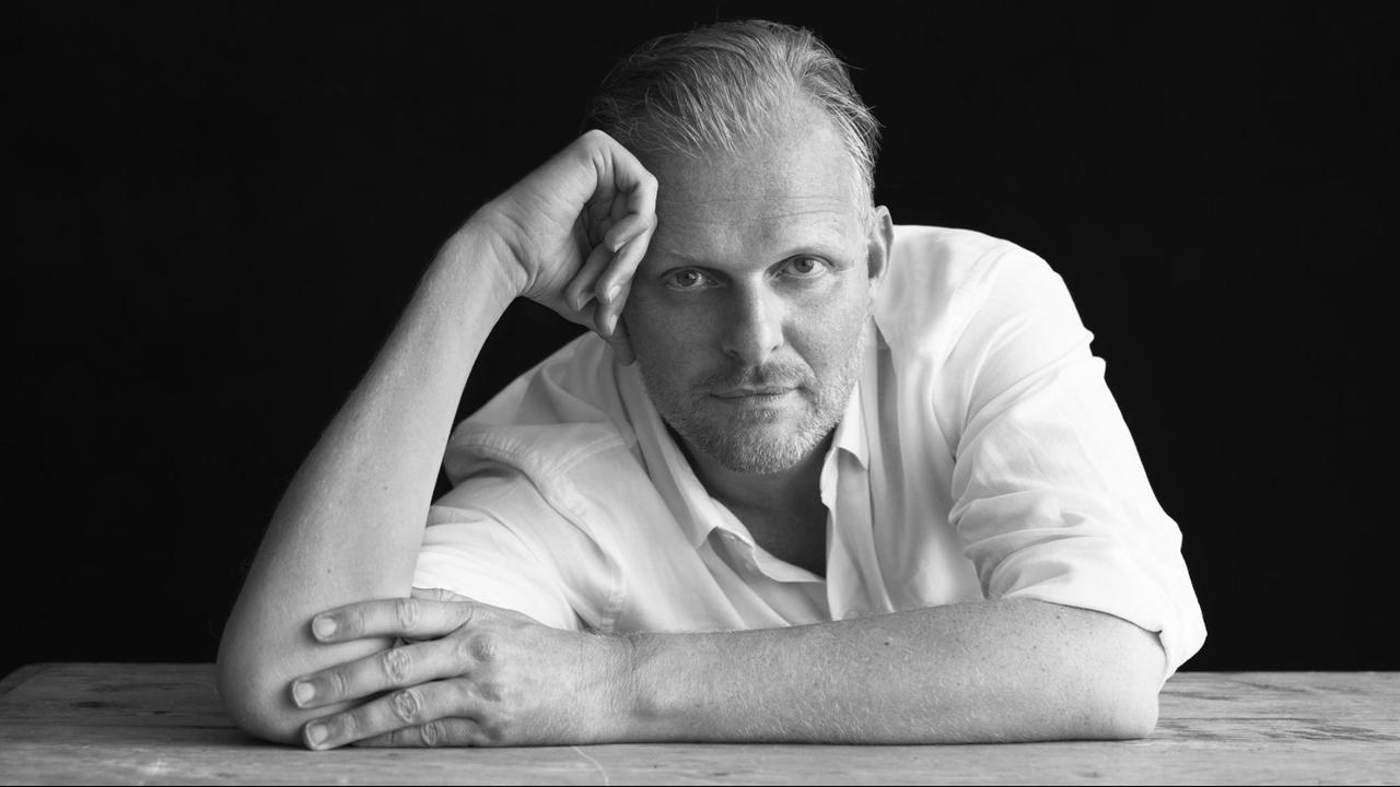 Schwarz-Weiß-Porträt von Thomas Ostermeier. Er stützt den Kopf auf einen Arm und schaut in die Kamera.