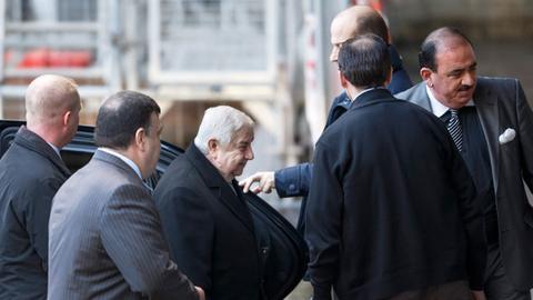 Der syrische Außenminister Walid al-Muallim steigt umringt von einer Schar Begleiter in Genf aus einem Auto. Er ist für die Syrien-Friedensverhandlungen angereist.