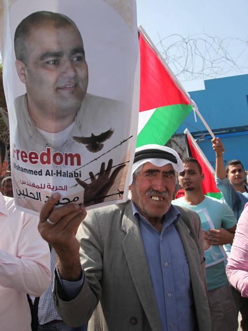 Palästinenser halten bei einer Solidaritätskundgebung für den verhafteten Direktor der US-Hilfsorganisation World Vision für den Gaza-Streifen, Mohammed el Halabi, vor dem Unesco-Sitz in Gaza (Stadt) am 16.10.2016 Fotos des Verhafteten in die Höhe.