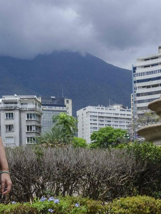 Eine Frau mit Schutzmaske steht trotzig auf einem Platz in Caracas.