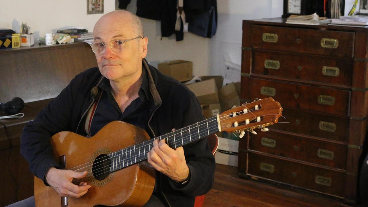 Thomas Pigor sitz mit seiner Gitarre in seiner berliner Wohnung 