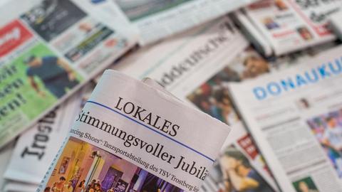 Eine Lokalzeitung wird über andere Zeitungen gehalten.