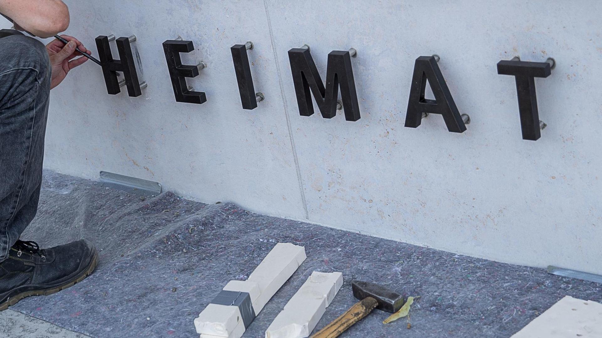 09.08.2018, Berlin: Handwerker befestigen die Buchstaben für das Wort "Heimat" am Eingang zum Dienstgebäude des "Bundesministerium des Innern, für Bau und Heimat"