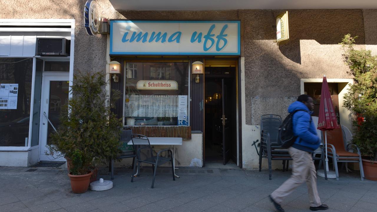 Ein Mann läuft am Eingang der Kneipe "Imma uff" in der Kantstrasse in Berlin- Charlottenburg vorbei. Vor dem Fenster steht ein Tischchen und ein Stuhl.