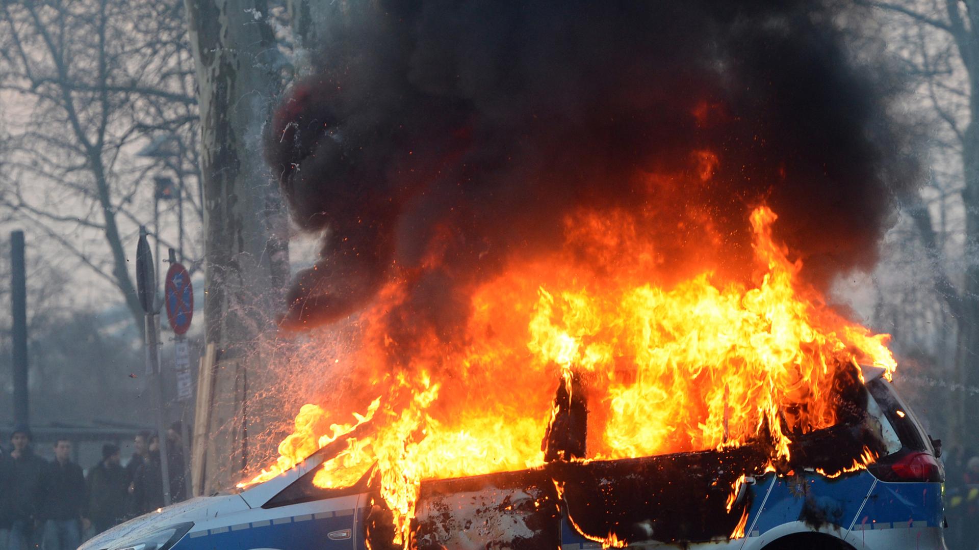 Ein brennendes Polizeiauto am Rande der Proteste