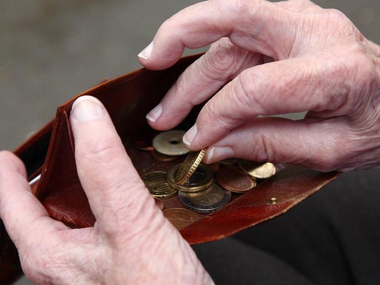 Eine Seniorin hält Geld in ihrer Hand.