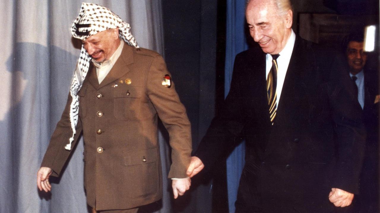 Shimon Peres und Yassir Arafat betreten Hand in Hand eine Bühne.