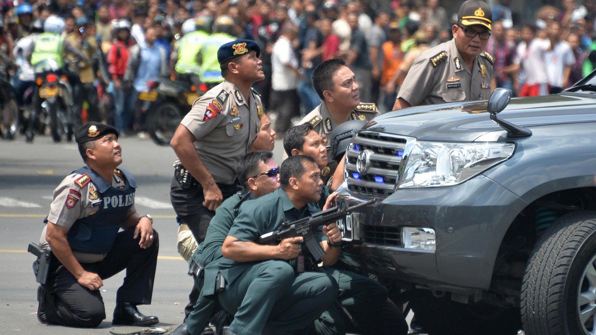 Indonesische Polizisten nehmen Deckung hinter einem Auto in der Hauptstadt Jakarta.