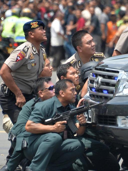 Indonesische Polizisten nehmen Deckung hinter einem Auto in der Hauptstadt Jakarta.