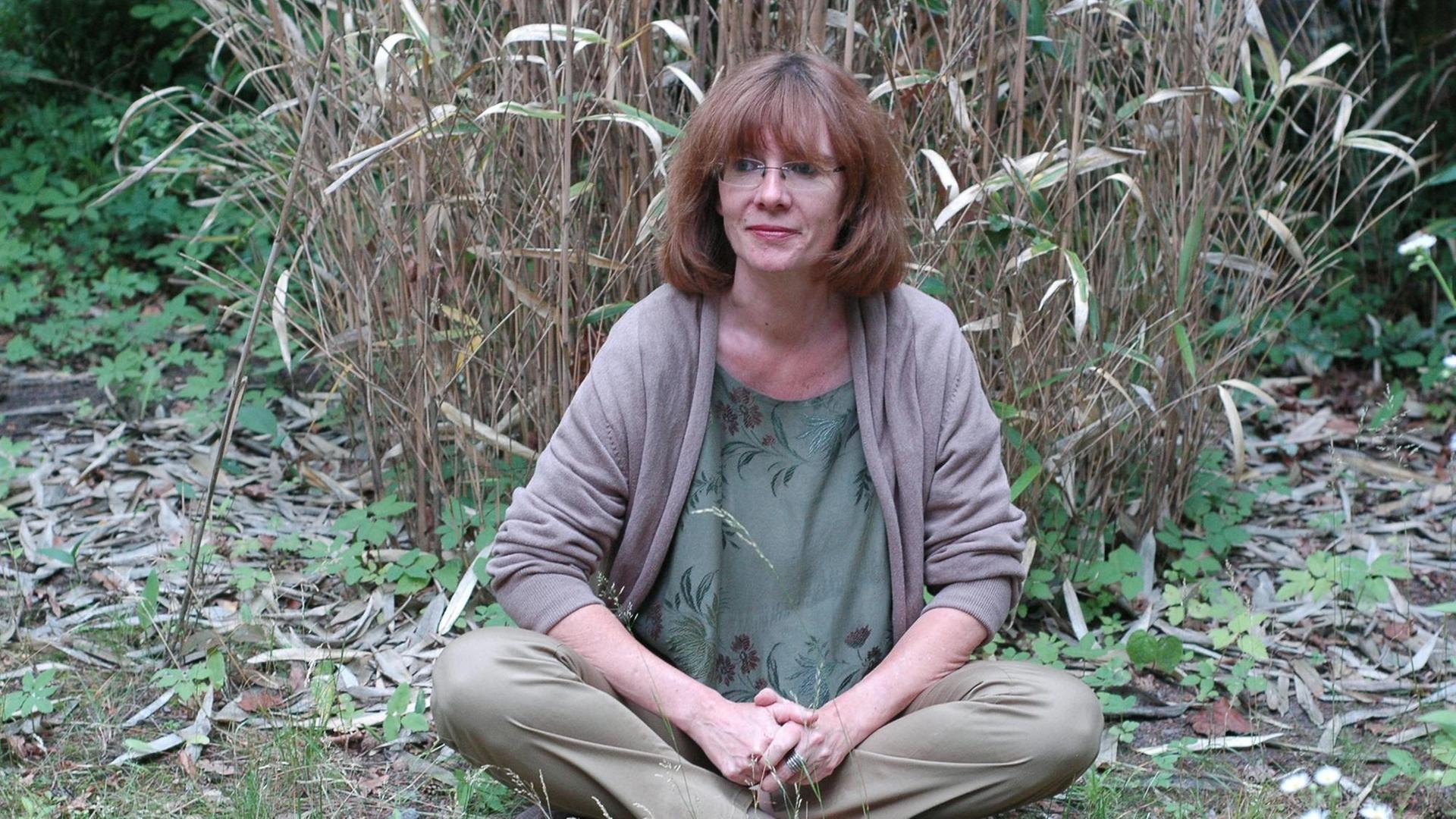 Die Schriftstellerin Patricia Görg sitzt in der Natur.