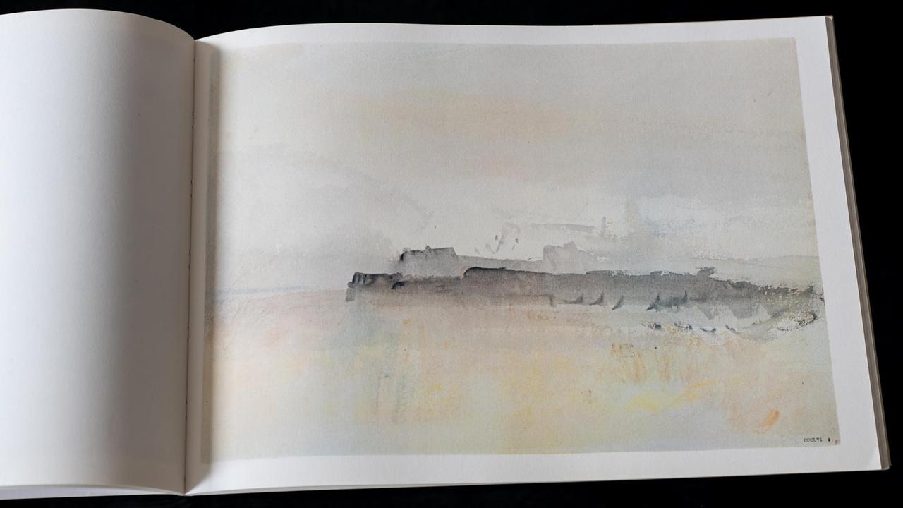 Ein aufgeschlagenes Buch, in dem ein Aquarell zu sehen ist. Im Hintergrund des Bildes sind Silhouetten von Gebäuden erkennbar.