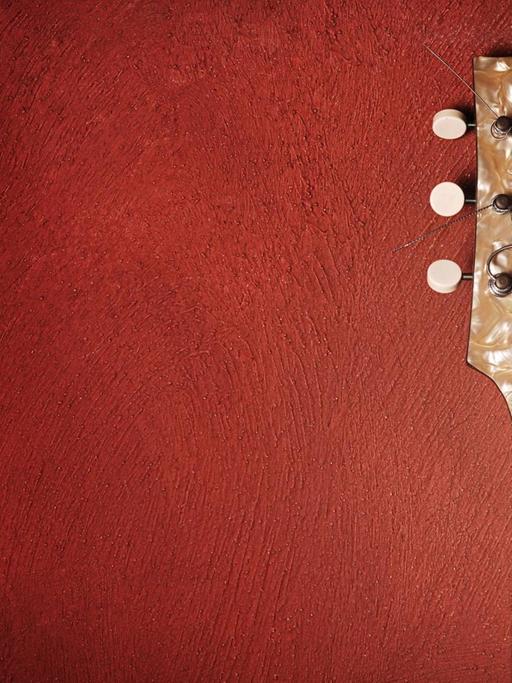 Gitarre lehnt gegen eine rote Wand