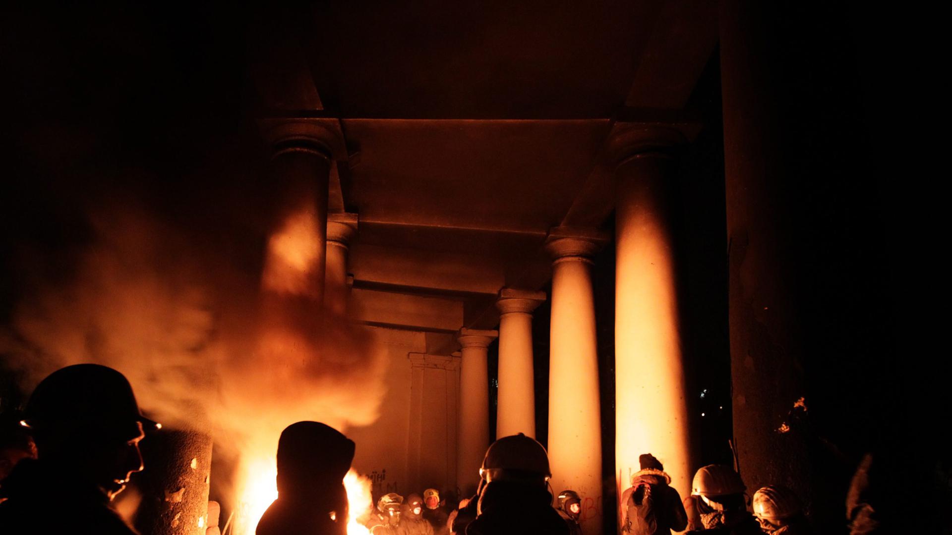Demonstranten in Kiew wärmen sich an einem Feuer in der Nacht Demonstranten in Kiew wärmen sich an einem Feuer in der Nacht