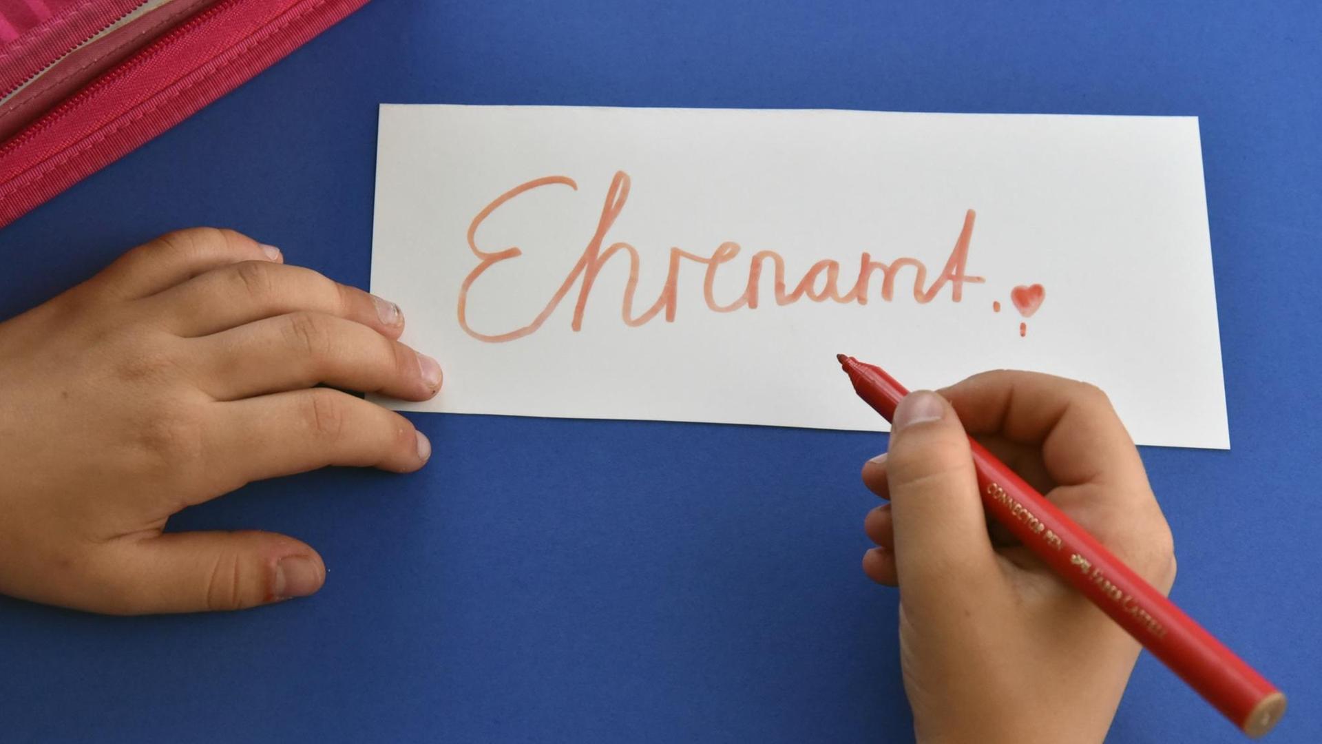Symbolfoto: Ein Schulkind schreibt das Wort "Ehrenamt" auf ein Blatt Papier (Foto vom 31.05.2016).