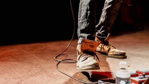 Der Fuß eines Gitarristen auf einem Effektpedal.