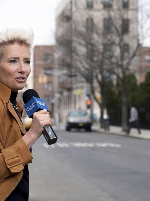 Eine Reporterin steht vor einer leeren Straße und spricht ins Mikrofon