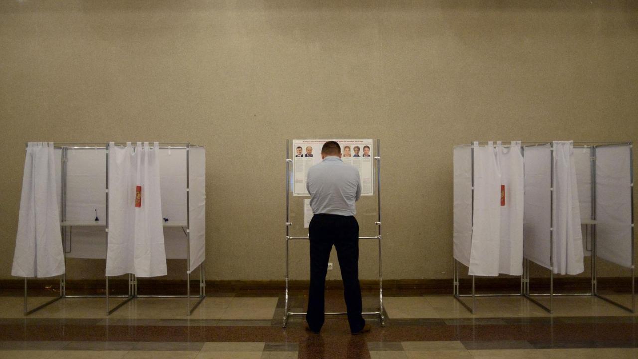 Ein Mann steht vor Wahlkabinen in Russland. Ein Mann steht vor Wahlkabinen in Russland.