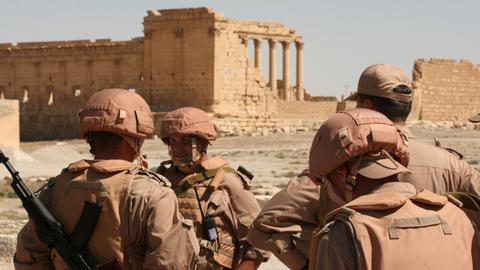 Russische Soldaten posieren vor antiken Ruinen der Wüstenstadt Palmyra in Syrien.