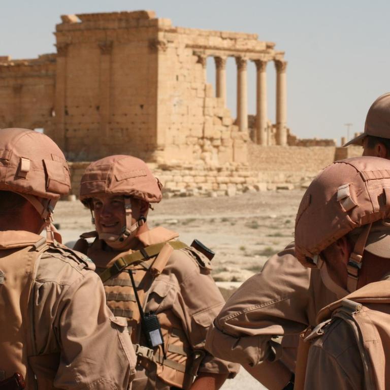 Russische Soldaten posieren vor antiken Ruinen der Wüstenstadt Palmyra in Syrien.