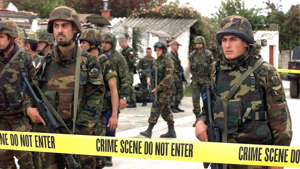 US-Soldaten hinter Flatterband - sie sperren ein Gelände, auf der Suche nach Spuren von Kriegsverbrechen (1999 im Kosovo).