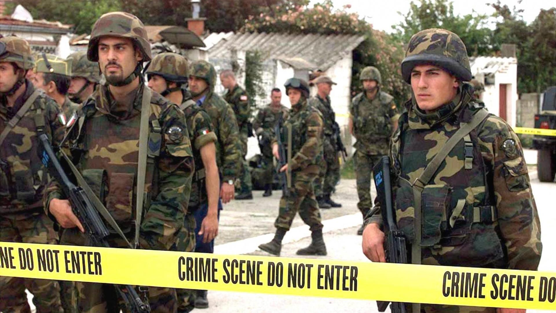 Auf der Suche nach Spuren von Kriegsverbrechen inspizieren US-Soldaten am 24.6.1999 ein abgesperrtes Gelände in Dakovica im Kosovo. Die mit unvorstellbarer Brutalität begangenen Greueltaten der serbischen Soldateska im Kosovo kommen immer mehr ans Tageslicht. Der stellvertretende Chefankläger des UN-Tribunals in Den Haag, Graham Blewitt, sagte am 23.6.1999, er rechne damit, daß schon bald alle vom Tribunal als vorrangig bezeichneten Orte von Massakern und anderen Verbrechen untersucht werden. Die Ermittlungen internationaler Experten vor Ort kämen gut voran. Der britische Außenminister Robin Cook, der am 23.6. ein Massengrab bei Velika Krusa in Augenschein nahm, sagte: «"Das hier ist entsetzlich. Ich bin tief bewegt und erschüttert."