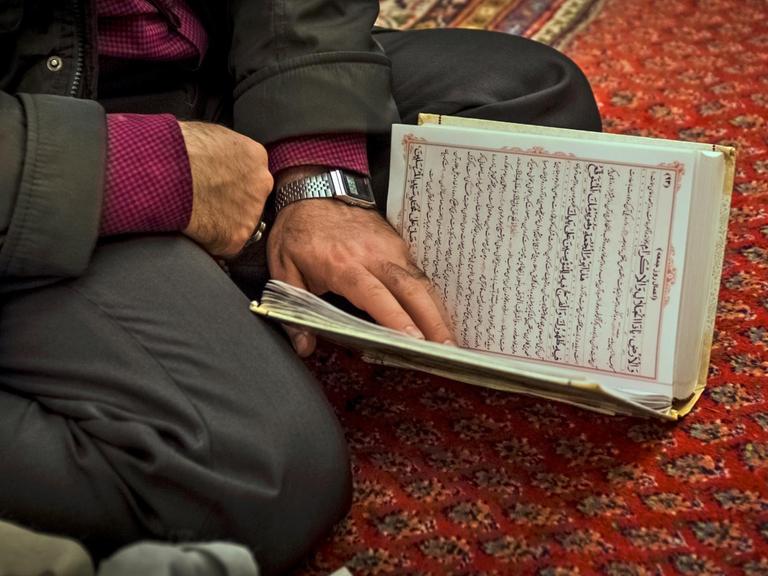 Ein iranischer Muslim liest während des Gottesdienstes in der Moschee im Koran.