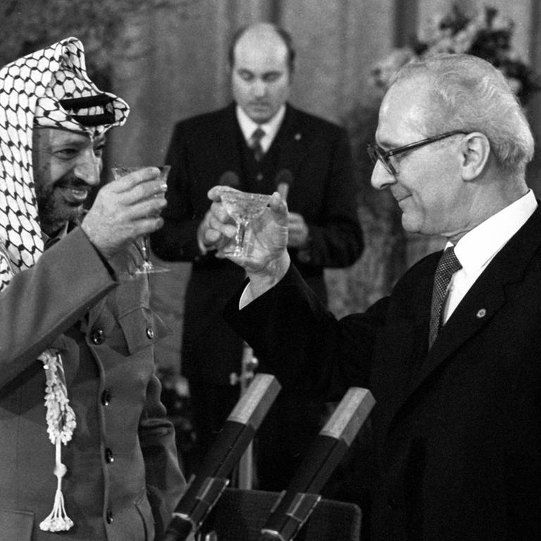 Staatsratsvorsitzender Erich Honecker und Yasser Arafat heben ihre Gläser zum Antoßen an.