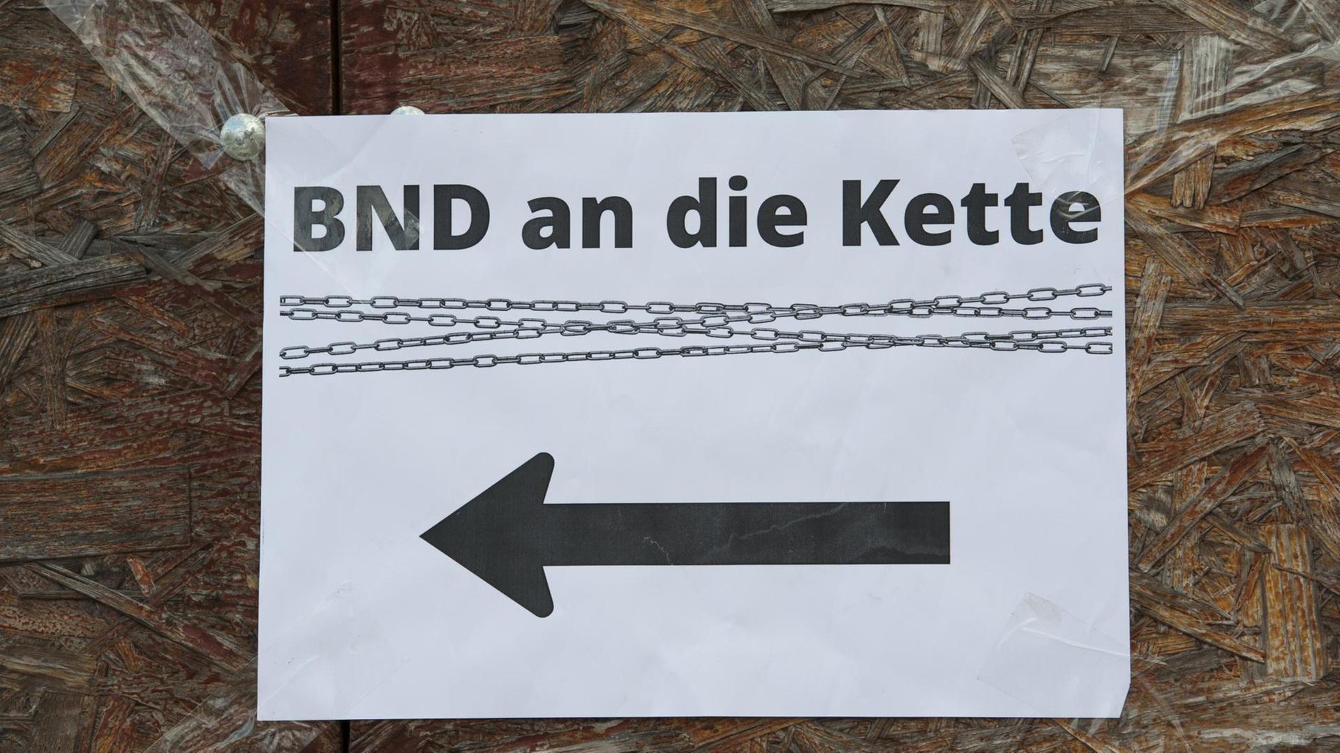 "BND an die Kette" steht in Berlin auf einem Plakat an einem Bauzaun des Neubaus des Bundesnachrichtendienstes (BND). Nach Angaben der Polizei demonstrierten vor dem Gebäudekomplex mehr als 100 Menschen gegen massenhafte Überwachung der Kommunikation durch internationale Geheimdienste.