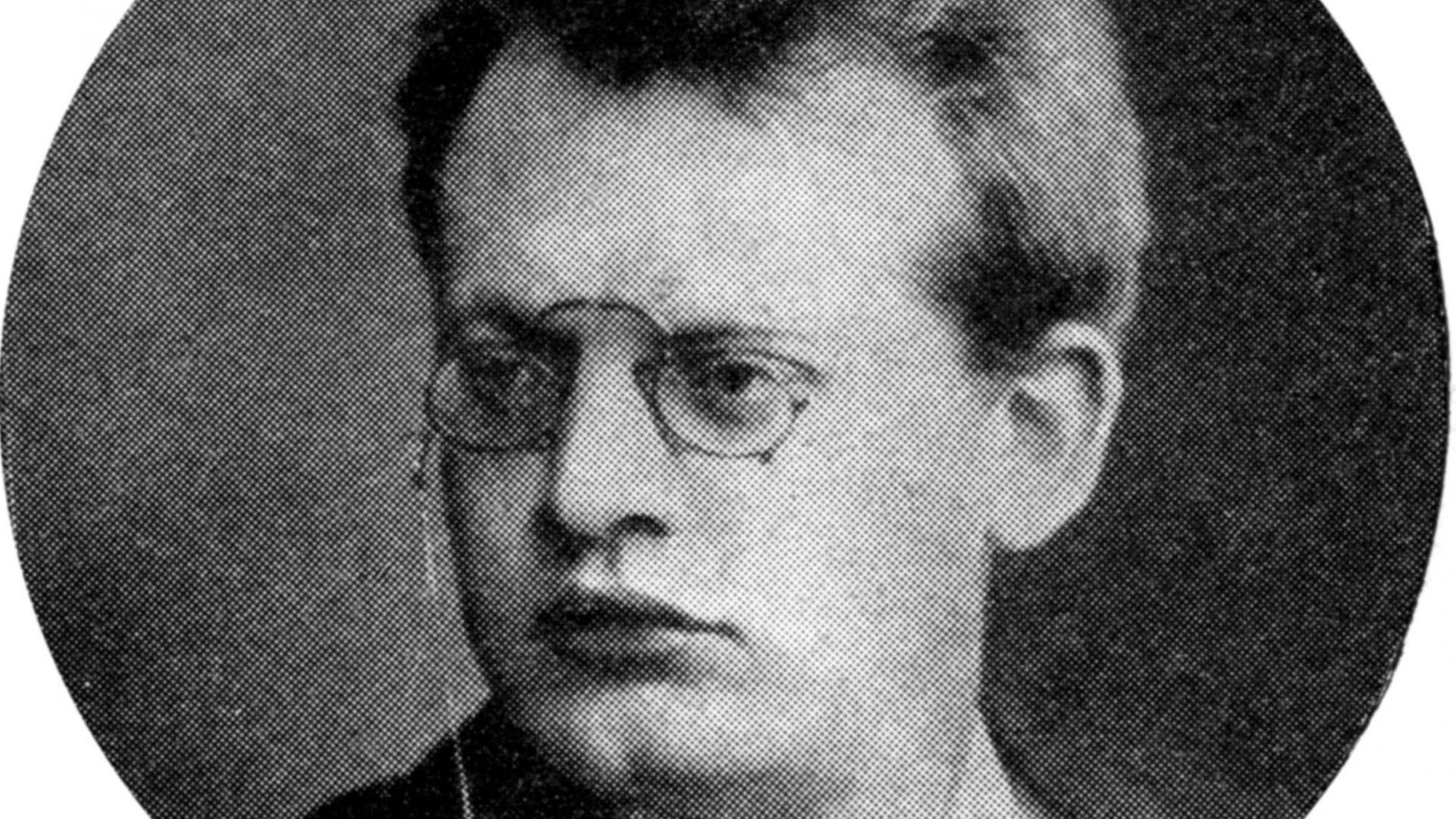 Schwarz-weiß-Aufnahme eines Mannes mit Brille, üppigen Lippen und einem ernsten Gesichtsausdruck.