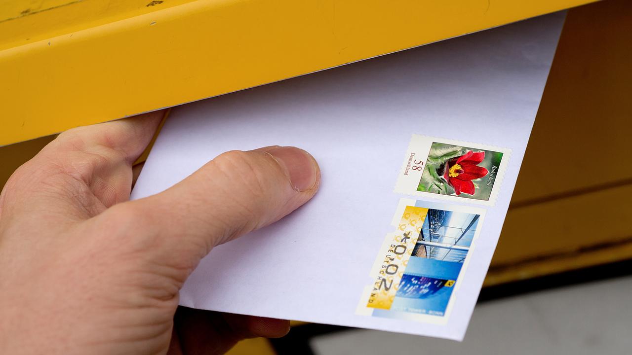 Ein Brief wird in einen Briefkasten gesteckt.
