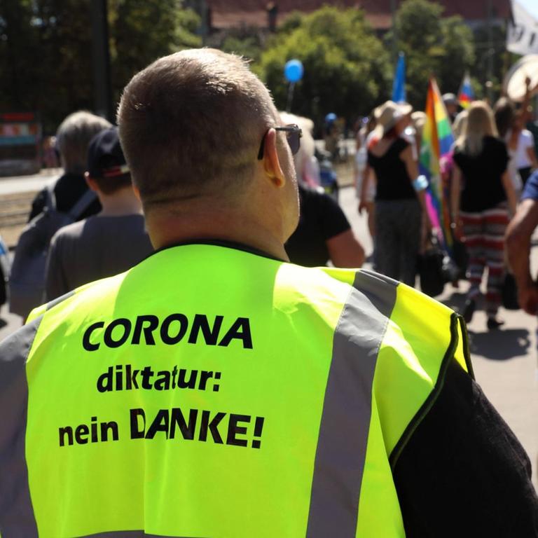 Auf der neongelben Jacke eines Demonstranten steht: "Corona-Diktatur Nein Danke".