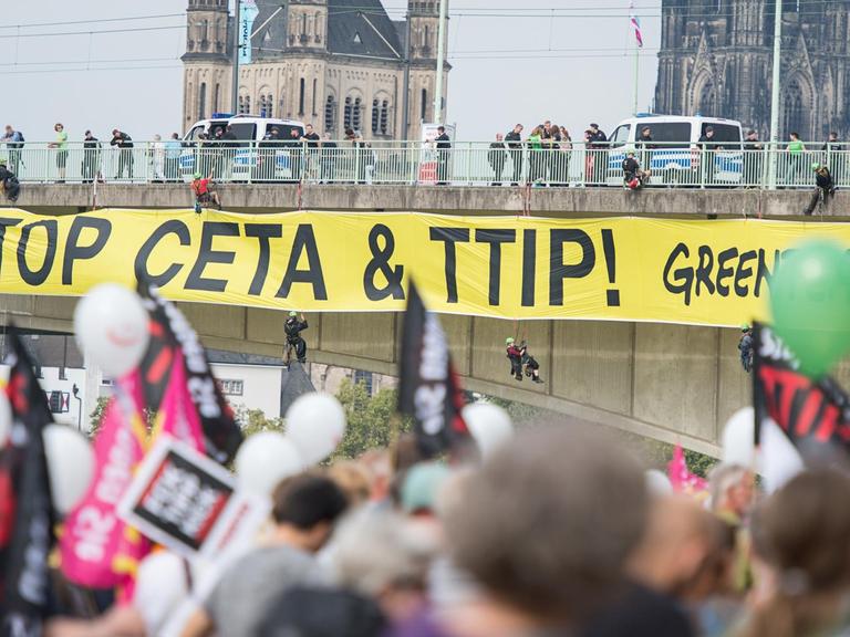 Aktivisten von Greanpeace bringen ein Banner an der Deutzer Brücke an am 17.09.2016, bei einer Demonstration gegen die Handelsabkommen CETA und TTIP in Köln (Nordrhein-Westfalen).