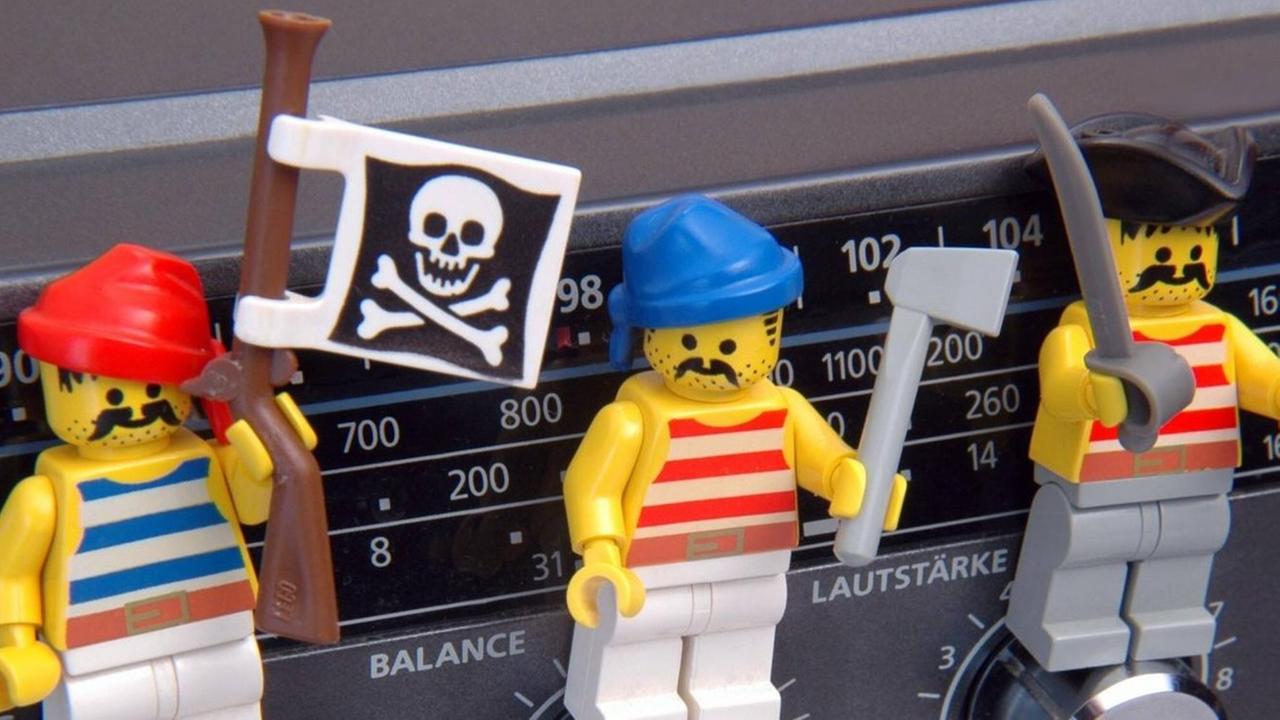 Drei Playmobilfiguren stehen auf Drehknöpfen eines Radios. Drei Playmobilfiguren stehen auf Drehknöpfen eines Radios.