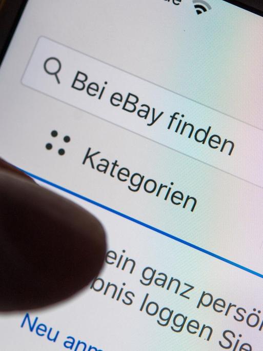 Eine Frau hält ein Smartphone mit der geöffneten ebay-App in der Hand