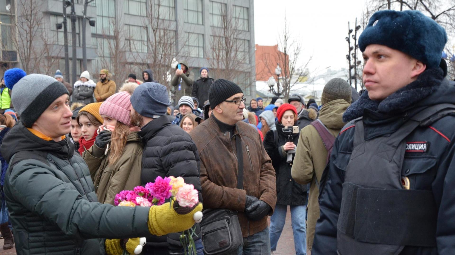 Auf einer nicht genehmigten Kundgebung der russischen Opposition in Moskau reicht ein Demonstrant einem Polizisten Blumen.