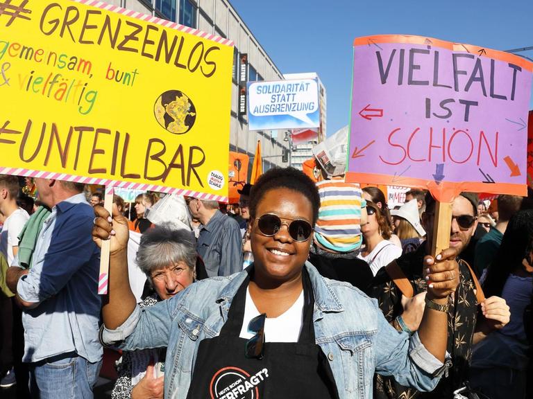 Eine Frau hält in einer Menge von Demonstrationen vor dem U-Bahnhof Alexanderplatz das Schild "Vielfalt ist schön" nach oben