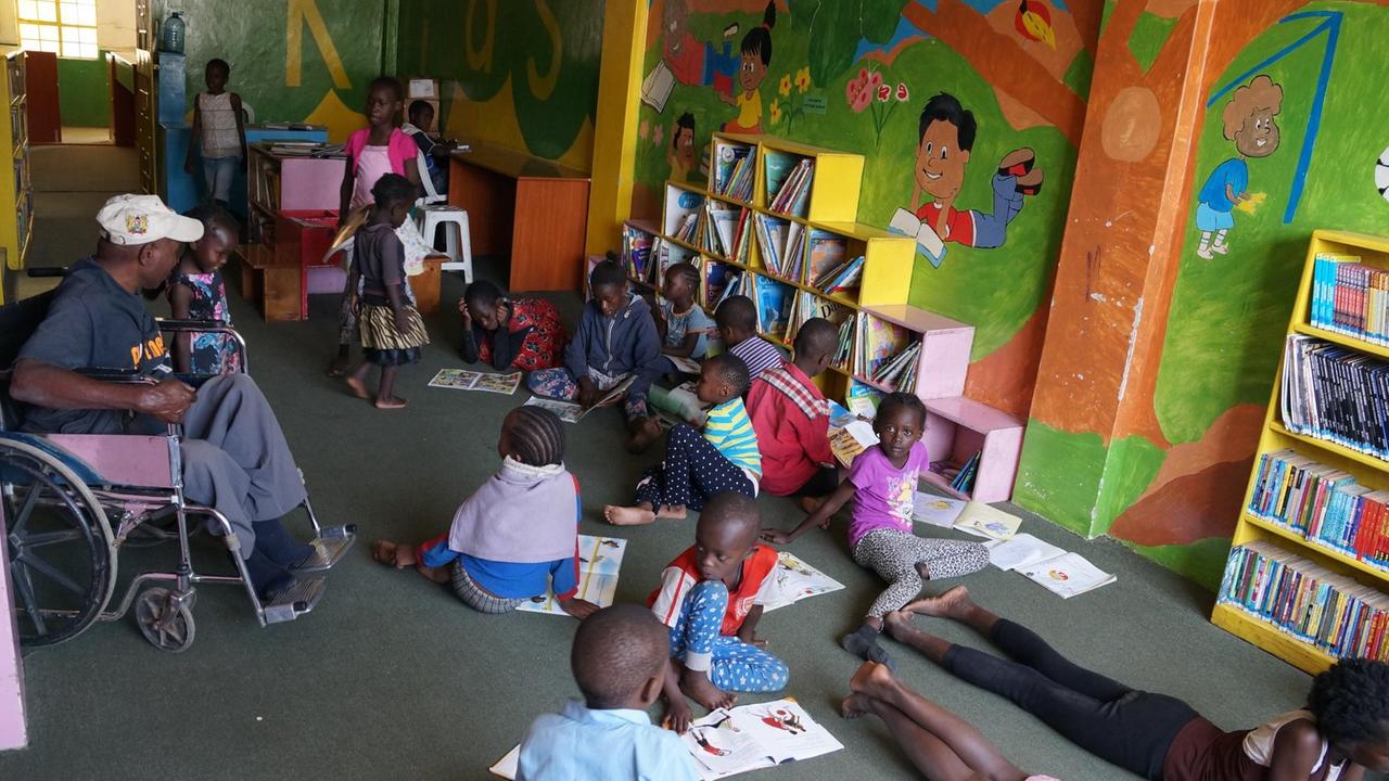 Kinder sitzen auf dem Boden der Bibliothek und schauen sich Bücher an
