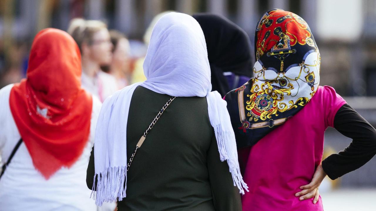 Rückenansicht von drei Frauen mit bunten Kopftüchern.