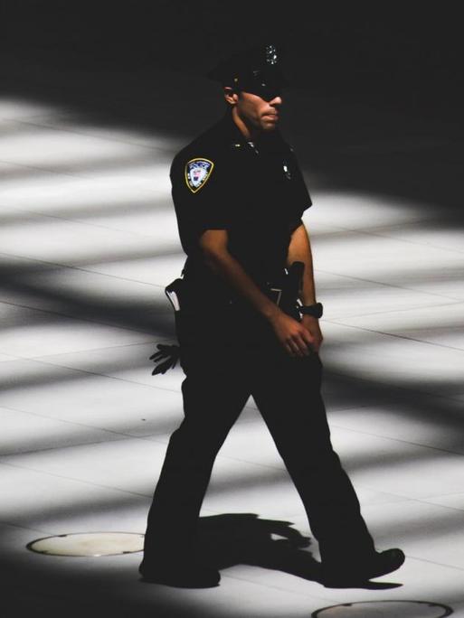 Ein Polizist läuft in New York einen Gehweg entlang.