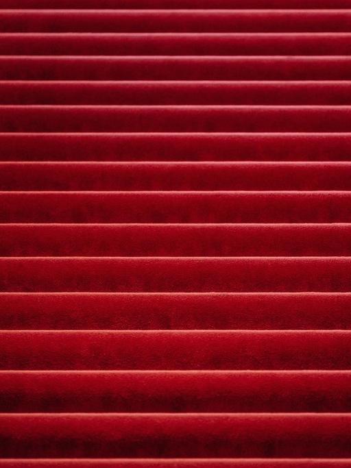 Ein roter Teppich bedeckt einen Teil der Treppenstufen, die auf einer großen Treppe nach oben führen.