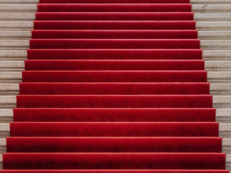 Ein roter Teppich bedeckt einen Teil der Treppenstufen, die auf einer großen Treppe nach oben führen.