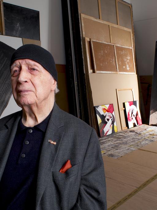 Karl Otto Götz im Alter von 85 Jahren in einem Atelier, im Hintergrund einige Gemälde.