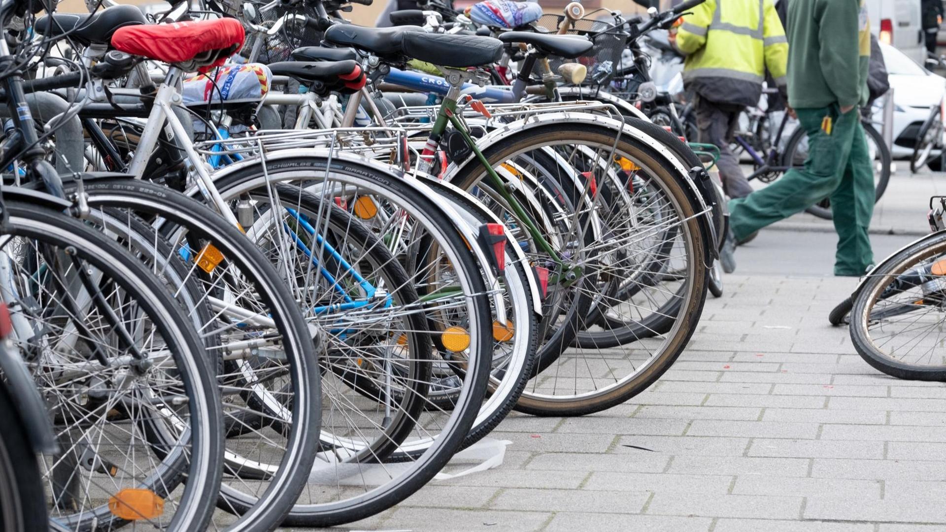 Vor einem Bahnhof stehen Fahrräder in langer Reihe in Fahrradständern, eins ist umgefallen Vor einem Bahnhof stehen Fahrräder in langer Reihe in Fahrradständern, eins ist umgefallen