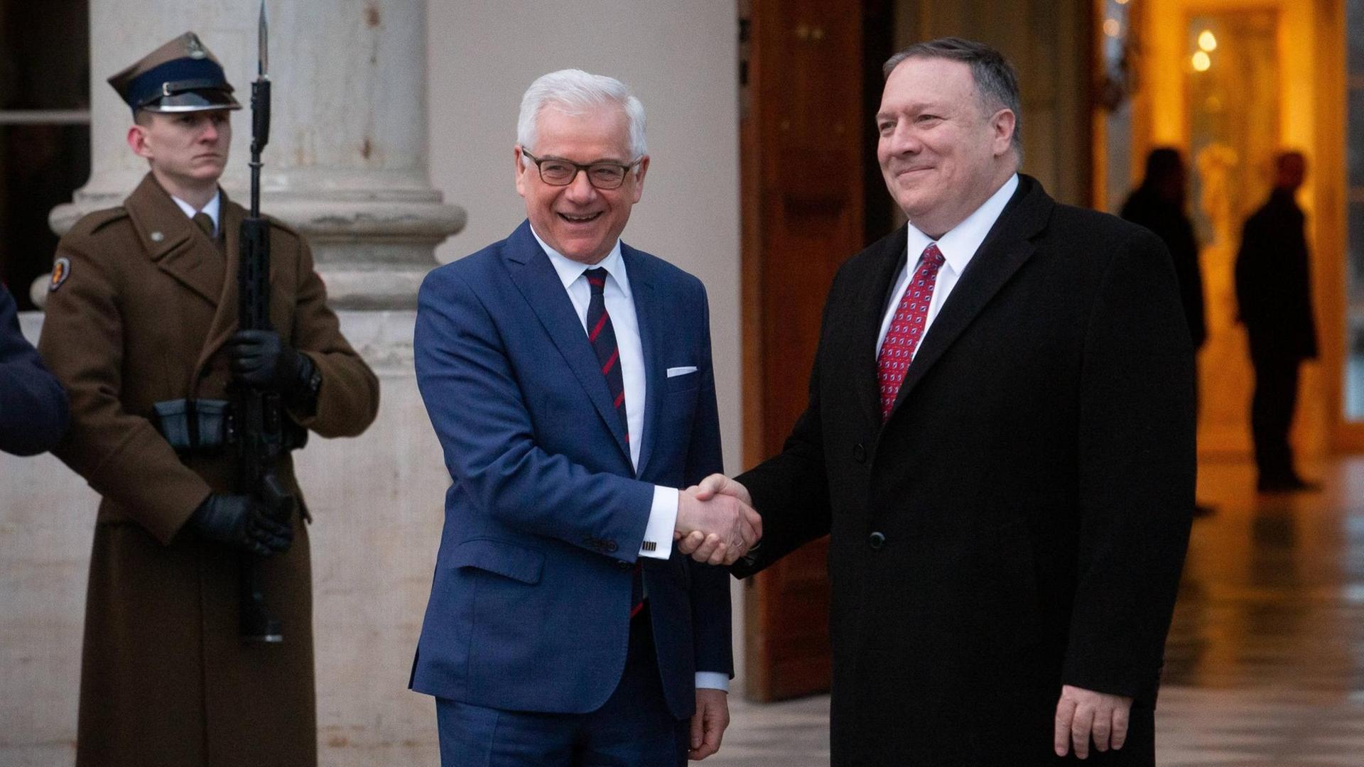Die Außenminister Polens und der USA, Jacek Czaputowicz (l) und Mike Pompeo (r), begrüßen sich mit Handschlag am 12.02.2019 im Lazienki Park, vor Beginn der Nahost-Konferenz in Warschau