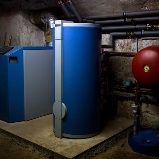 Ein Heizkessel einer etwa sechs Jahre alten Anlage und ein Warmwasserboiler stehen in einem Heizkeller.