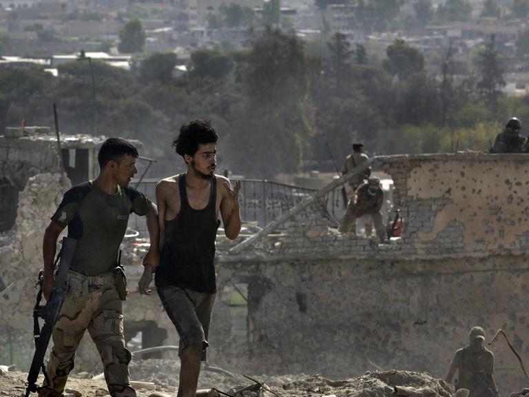 July 18, 2017. Mosul, Iraq: ISIS fighter is led away after surrendering to Iraqi Army soldiers on July 18, 2017 amid ruins of the Old City.